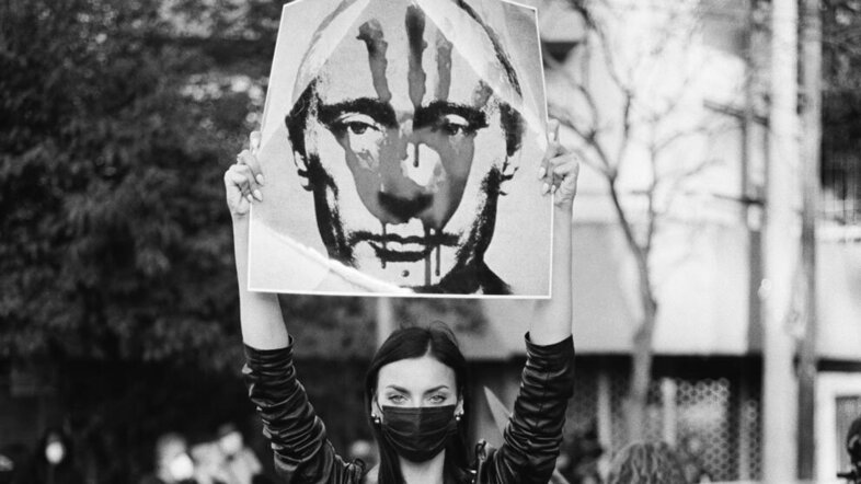 Frau hält Anti-Putin Banner in die Höhe