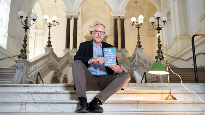 Photo of Mark Coeckelbergh sitting on the philosophers' steps in the main building of the University