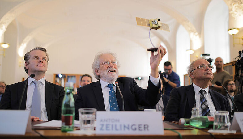 Anton Zeilinger (centre) holding a model of the "Micius" satellite, with Rector Heinz W. Engl to his right.