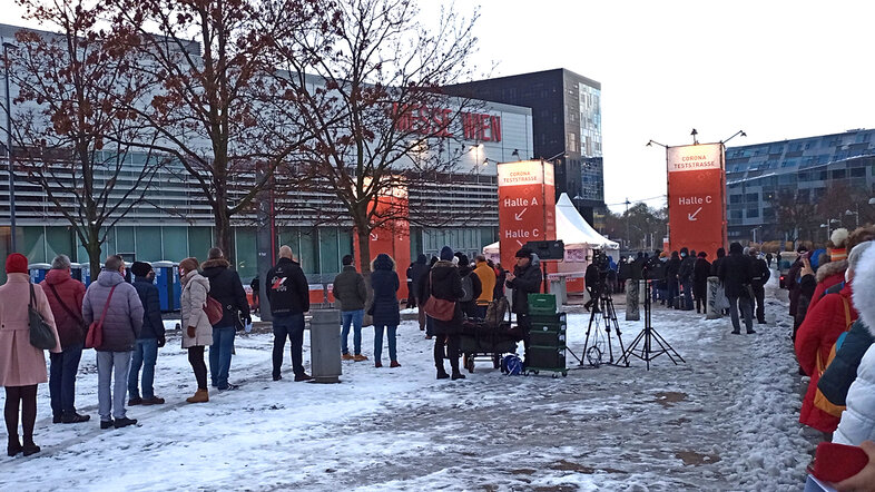 Menschen stehen im Schnee vor der Messe Wien an um auf das Coronavirus getestet zu werden.
