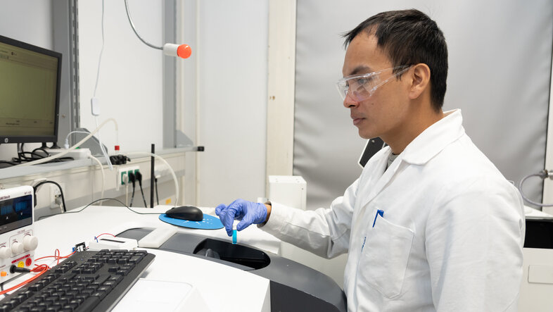 Ein Wissenschafter mit einer blauen Flüssigkeit an einem technischen Gerät