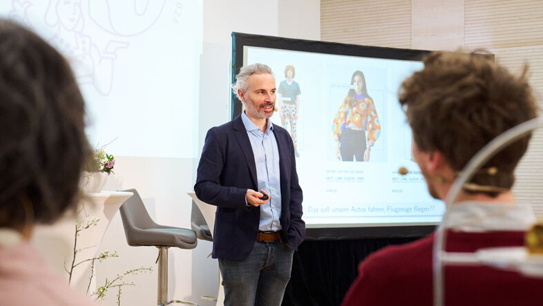 Philipp Grohs bei einem Vortrag, neben einem Screen mit einer Präsentation