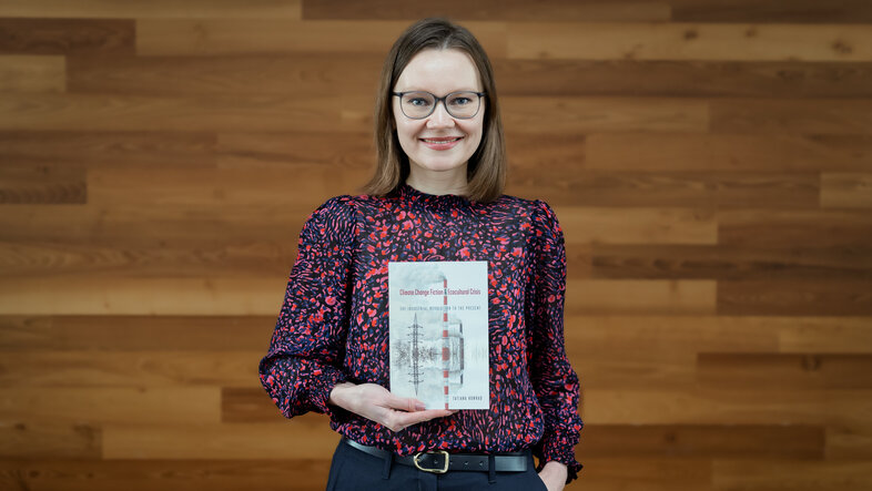 Cultural studies scholar Tatiana Konrad poses for a photo holding up her new book