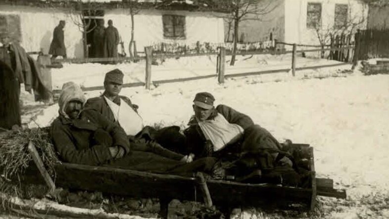 Drei verwundete Soldaten liegen auf einer Barre im Freien