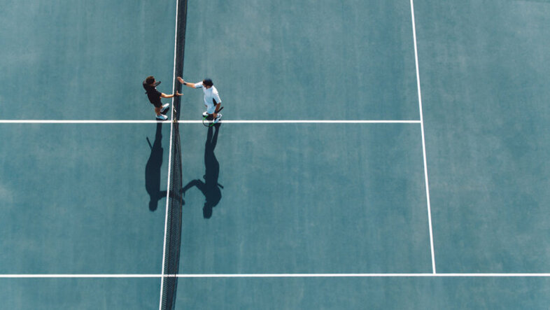 Stock photo of two tennis players standing at the net for a shake hands