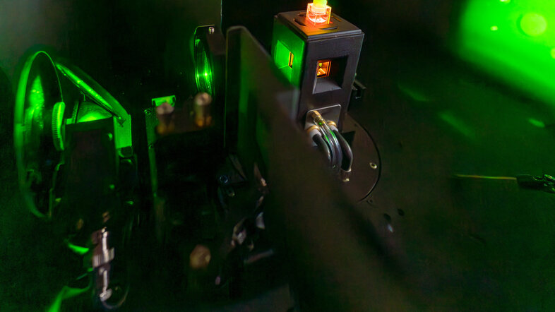 Eine Probe mit einer roten Flüssigkeit in einem Probenhalter wird mit grünem Laserlicht bestrahlt