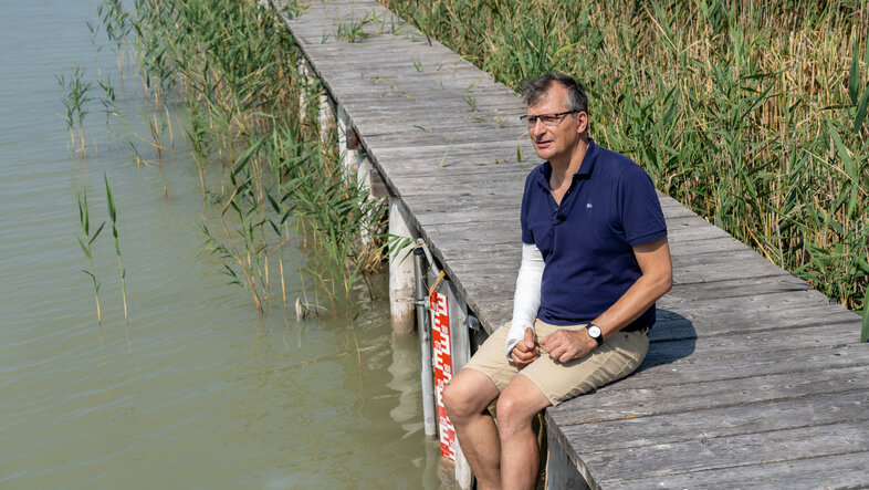 Stephan Glatzel sitze auf einem Holzsteg am Neusiedler See