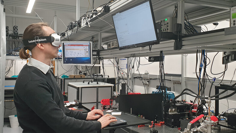 Oliver Heckl arbeitet stehend am Computer. Er trägt eine Schutzbrille von LaserVision.