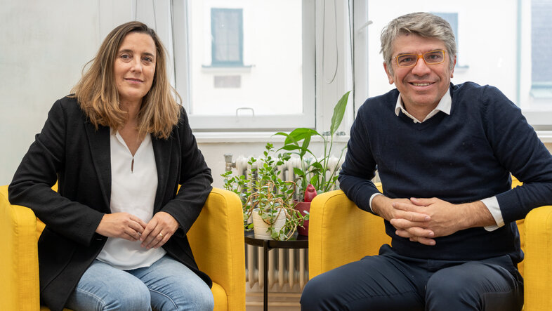 Portrait of Leticia Gonzalez and Davide Bonifazi on yellow chairs in the office