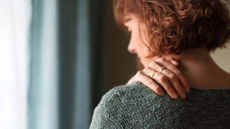 Woman from the back putting her hand on her left shoulder