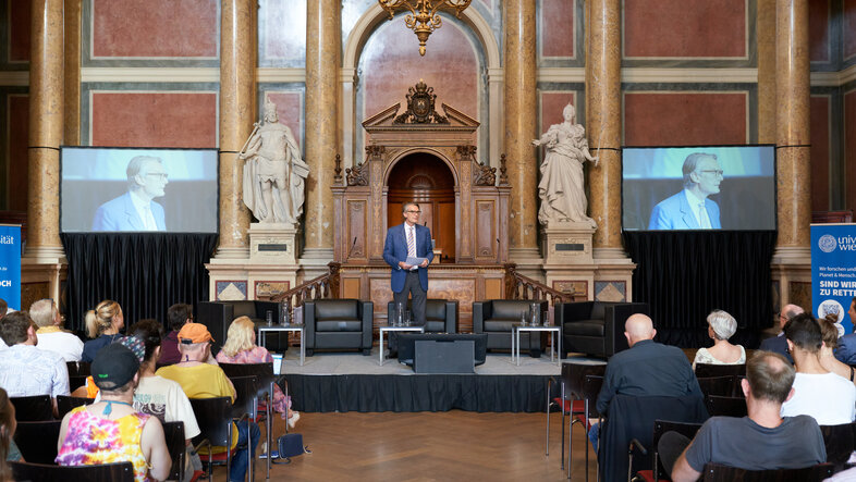 Rektor Sebastian Schütze begrüßt das Publikum der Podiumsdikussion im Großen Festsaal der Universität Wien.