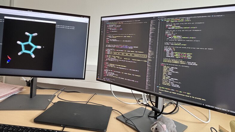 photo of a desk work station with two screens. a chemical structure is shown on the left screen