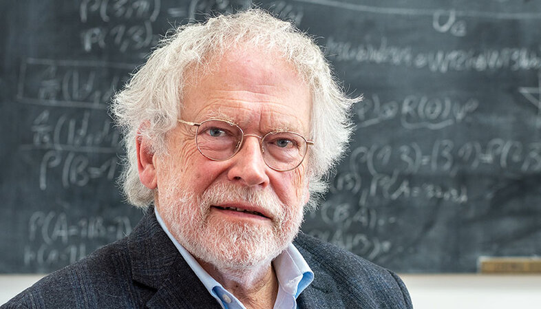 Portrait photo of Anton Zeilinger in front of a blackboard full of formulae