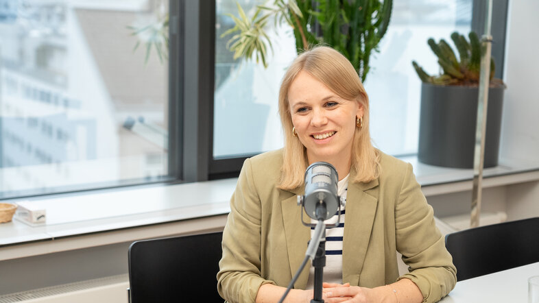 Desirée Schmuck sitzt vor einem Mikrofon beim Podcast-Interview im Publizistik-Institut