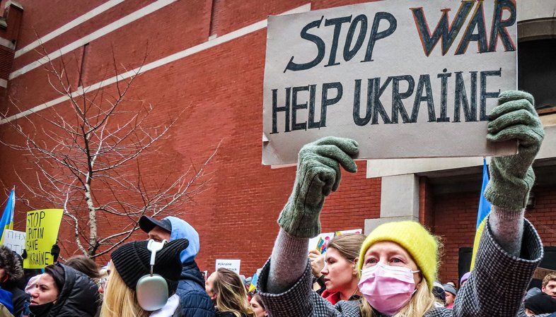 Frau hält Schild mit der Aufschrift "Stop War Help Ukraine"