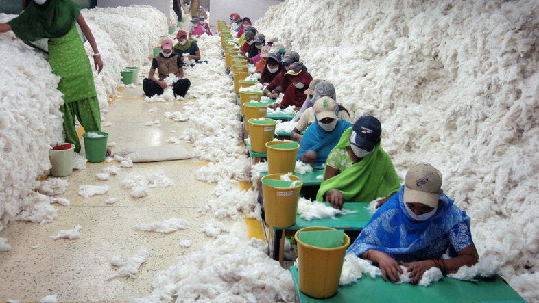 Arbeiter*innen säubern Baumwolle für die Weiterverarbeitung in einer Spinnerei. Indien, 2010 