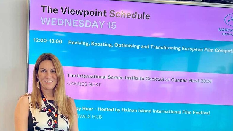 Katharine Sarikakis in Cannes, standing in front of the announcement of her talk