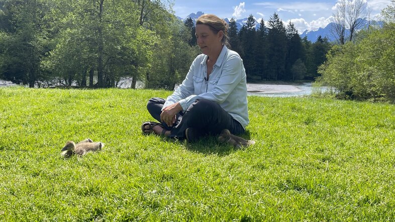 Sonia Kleindorfer sitzt auf einer Wiese, vor ihr ein Gössling